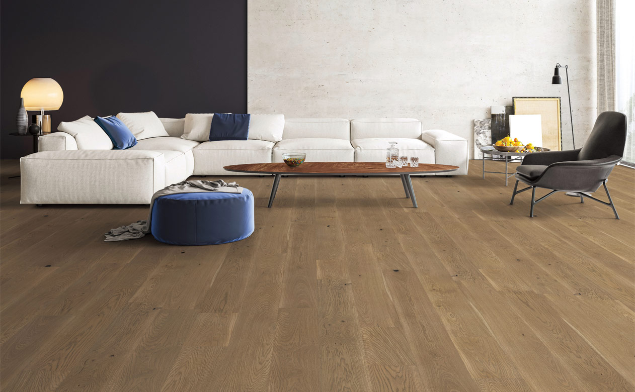 warm toned hardwood flooring in living room with large white couch and blue decor.