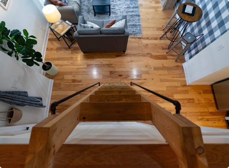 ladder view going down to living room with wood flooring